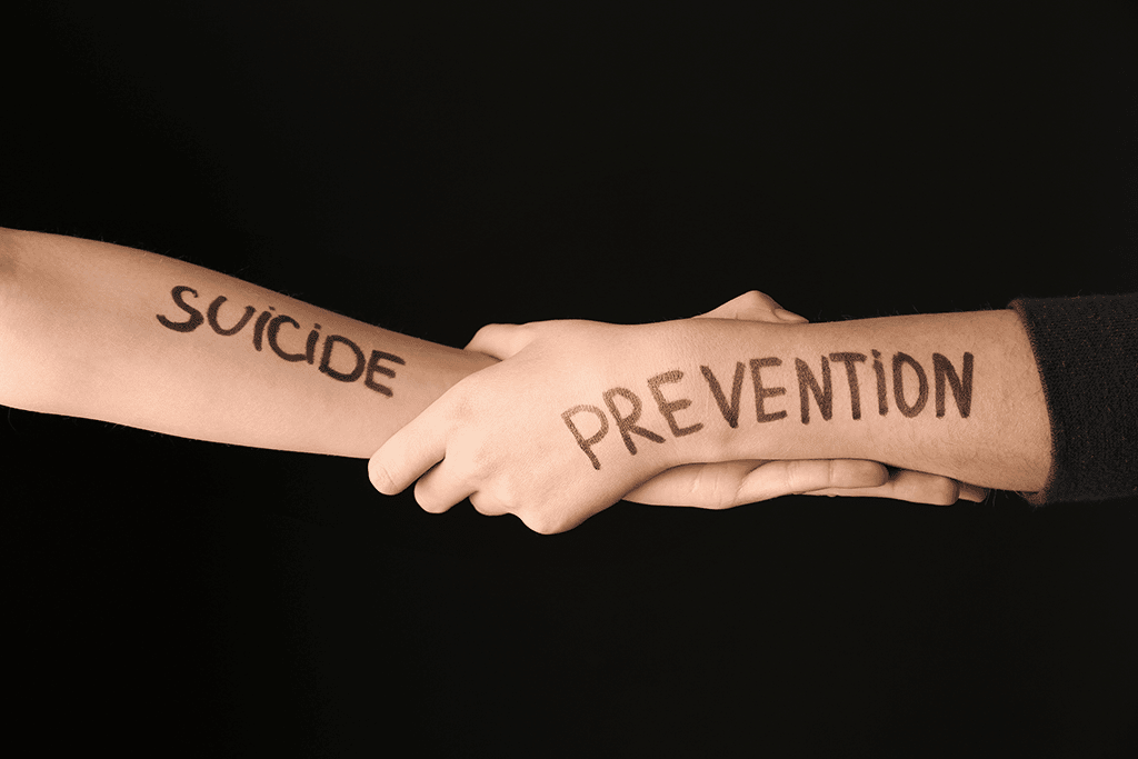 people holding arms with suicide prevention written on them