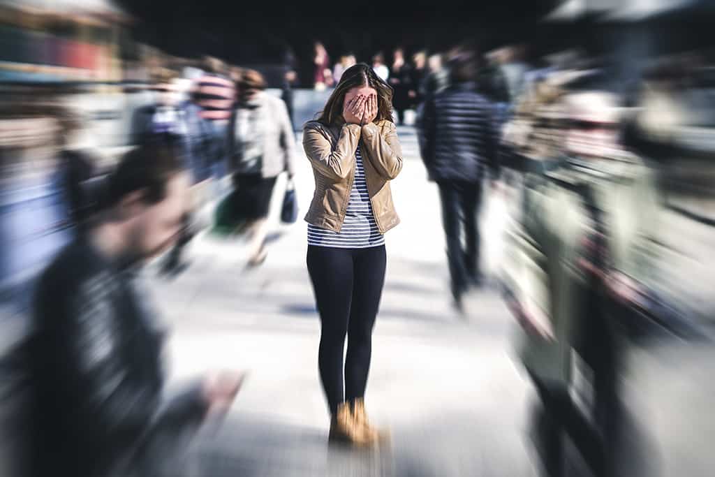 Woman having anxiety attack in busy city surrounded by people.