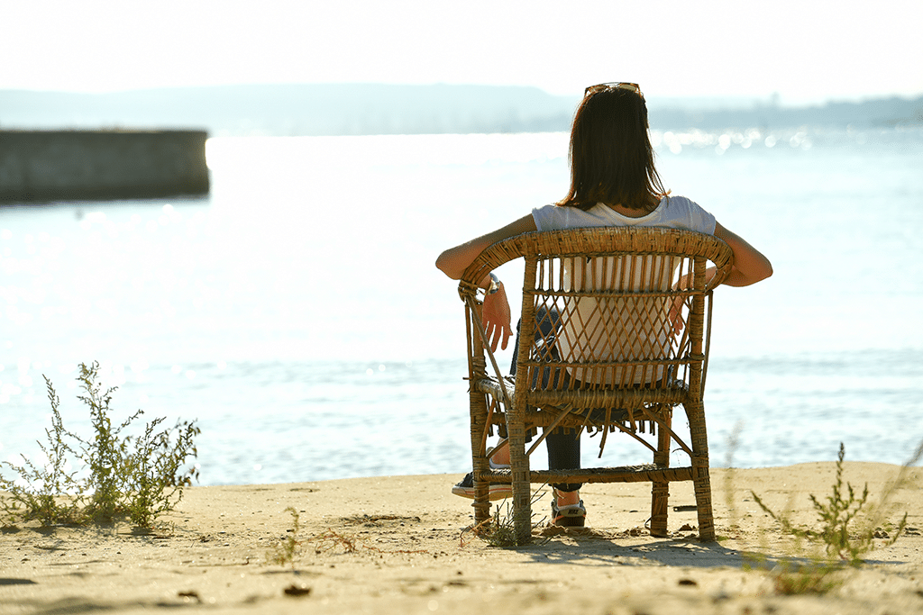 Woman sitting on a chair by the water during the summer